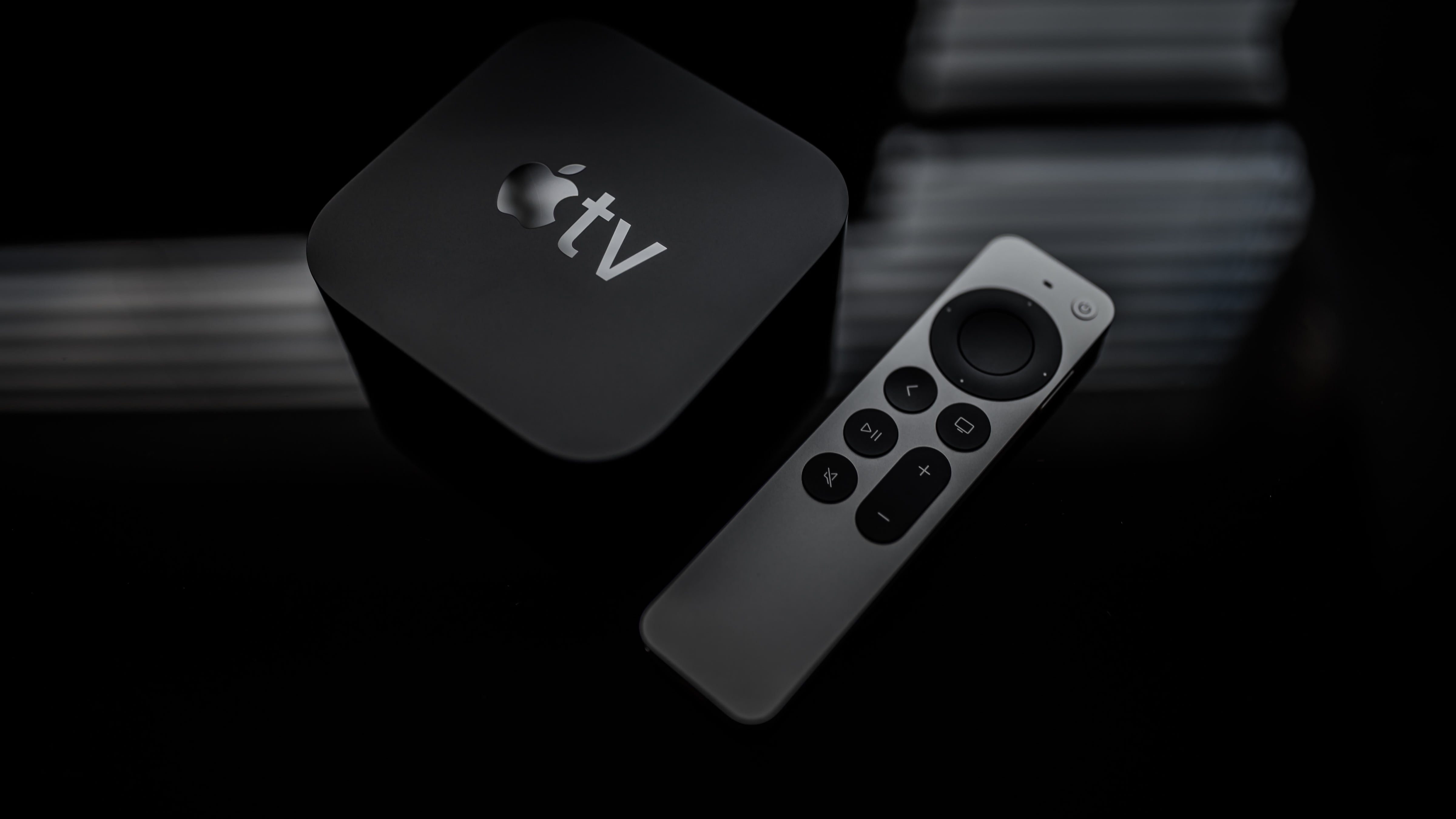 عرض بزاوية من أعلى لأسفل لجهاز Apple TV 4K من الجيل الثاني جنبًا إلى جنب مع Siri Remote محدث ، على خلفية مظلمة