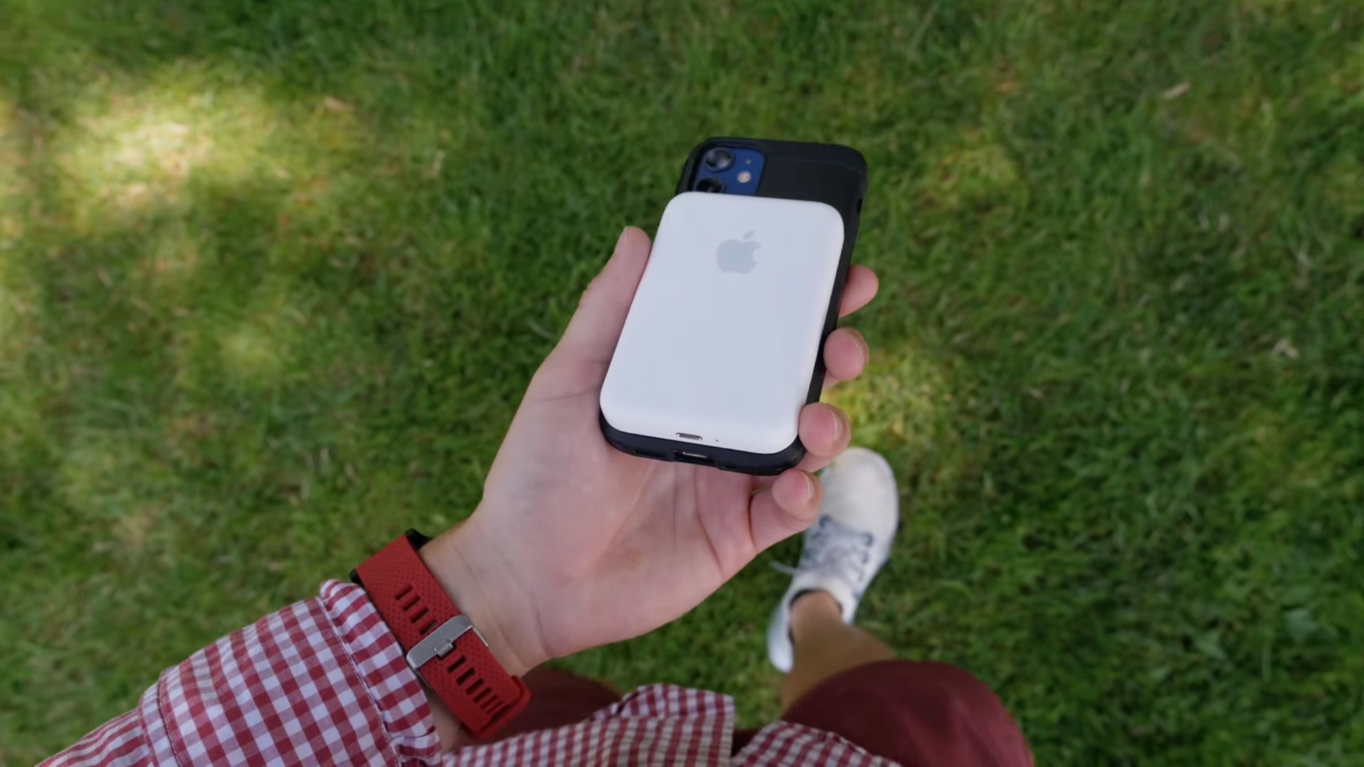 يُرى MagSafe Battery Pack من Apple عالقة في الجزء الخلفي من جهاز iPhone ، والذي يستريح في راحة يد شاب ، في هذه الصورة الثابتة المأخوذة من مراجعة فيديو iDB للملحق
